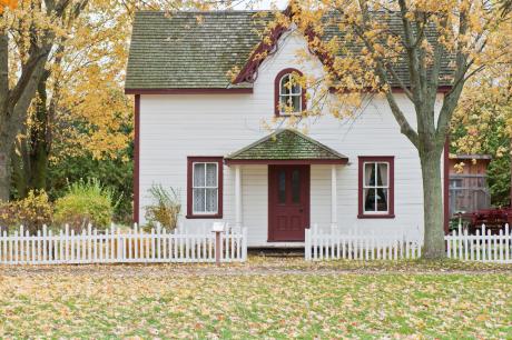 White house with red trim and door and a small white fence