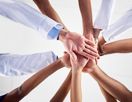 Low angle shot of a diverse team of healthcare providers and community workers joining their hands together