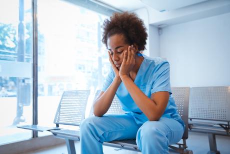 CNA holds her head in her hands, looks sad