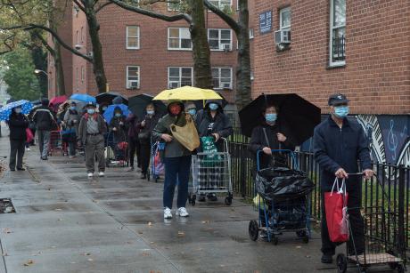 Queens, New York. October 28, 2020. A large crowd of people wait in line outside an outdoor food pantry in Woodside organized by "Sunnyside Community Services"