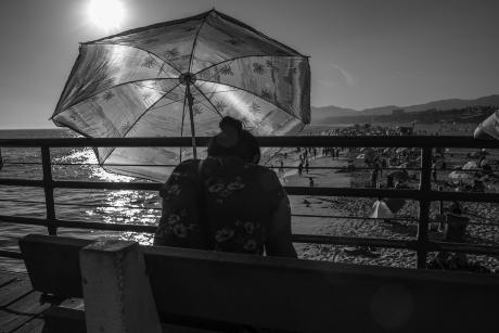 Woman sits on a bench overlooking a beach