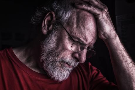 Sad older man holds his head