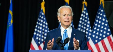 Joe Biden speaking at podium in front of US flags