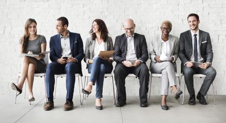 Age diverse coworkers sitting in a row, smilling