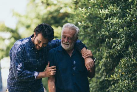 Son walking with father outside, arm around him