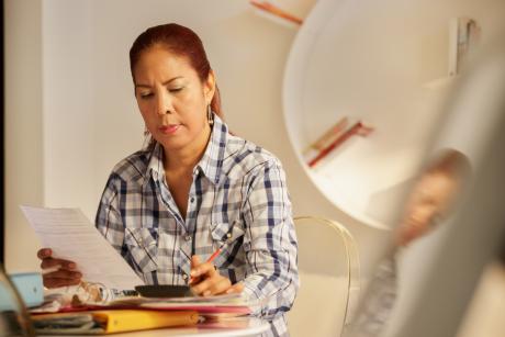 An older Latina fills out forms at a desk