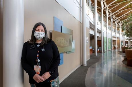 Blythe Winchester, wearing a face covering, standing in the lobby of a large building.