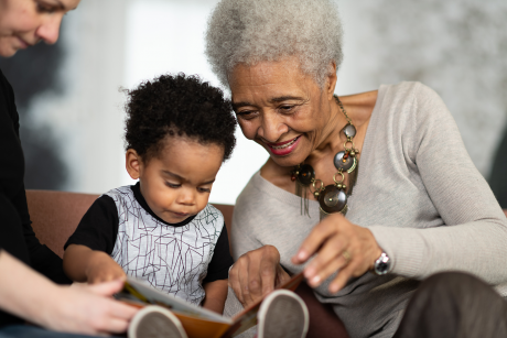 Grandmother reads with grandson, mother helps