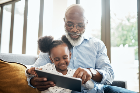 Granddaughter and grandfather reading together on iPad
