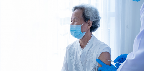 blown out photo of older Asian woman getting vaccinated