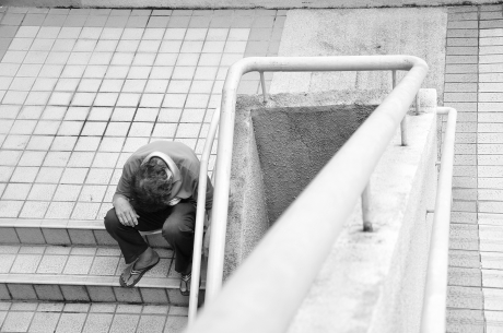 Homeless man looking down stairs, illustrating over the edge