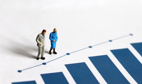 Miniature older adults facing blue bar chart
