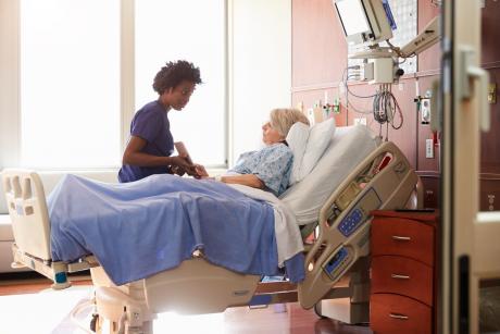 Nurse showing older adult tablet in hospital