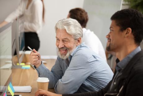 Older white office worker with younger colleague of color