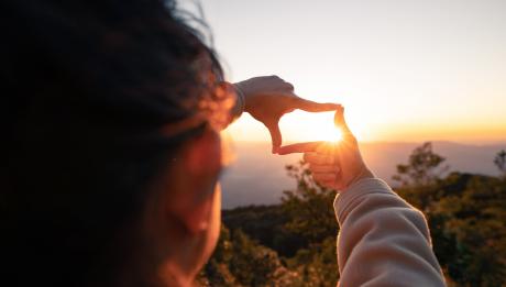 Woman framing sun with hands